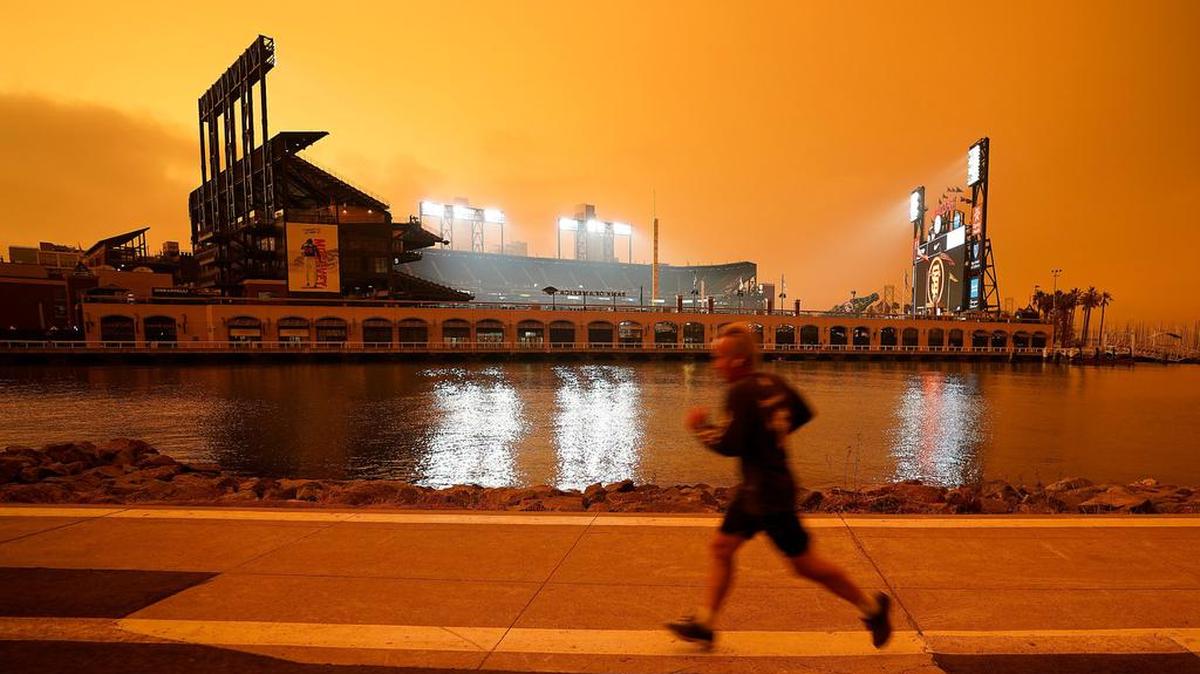 A jogger runs along McCovey Cove outside Oracle Park in San Francisco under skies darkened by wildfire smoke. An unprecedented Pacific Northwest and Canadian heat wave hit last summer, which a previous study showed couldn’t have happened without human-caused climate change.