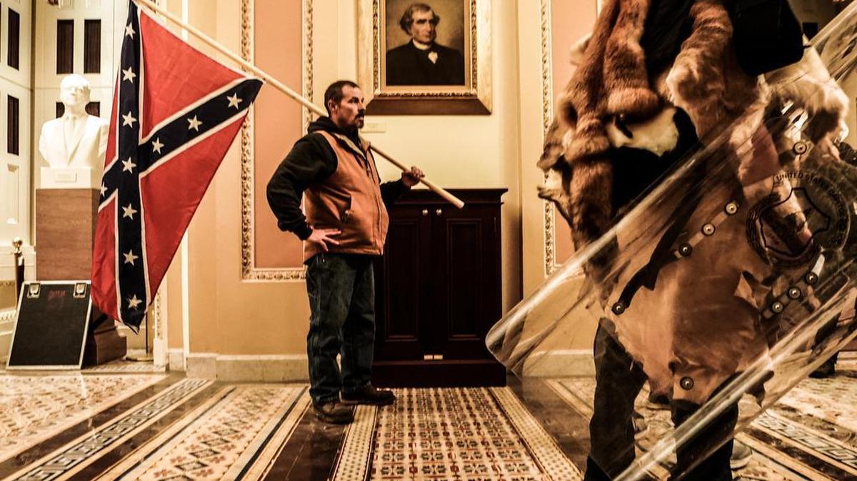 A rioter carries a Confederate flag in the Capitol in Washington during the insurrection on Jan. 6, 2021. Black Capitol Police officers have described the intense racism they endured from the mob, with one telling Buzzfeed News he was called a racist slur 15 times, causing him to break down in tears.