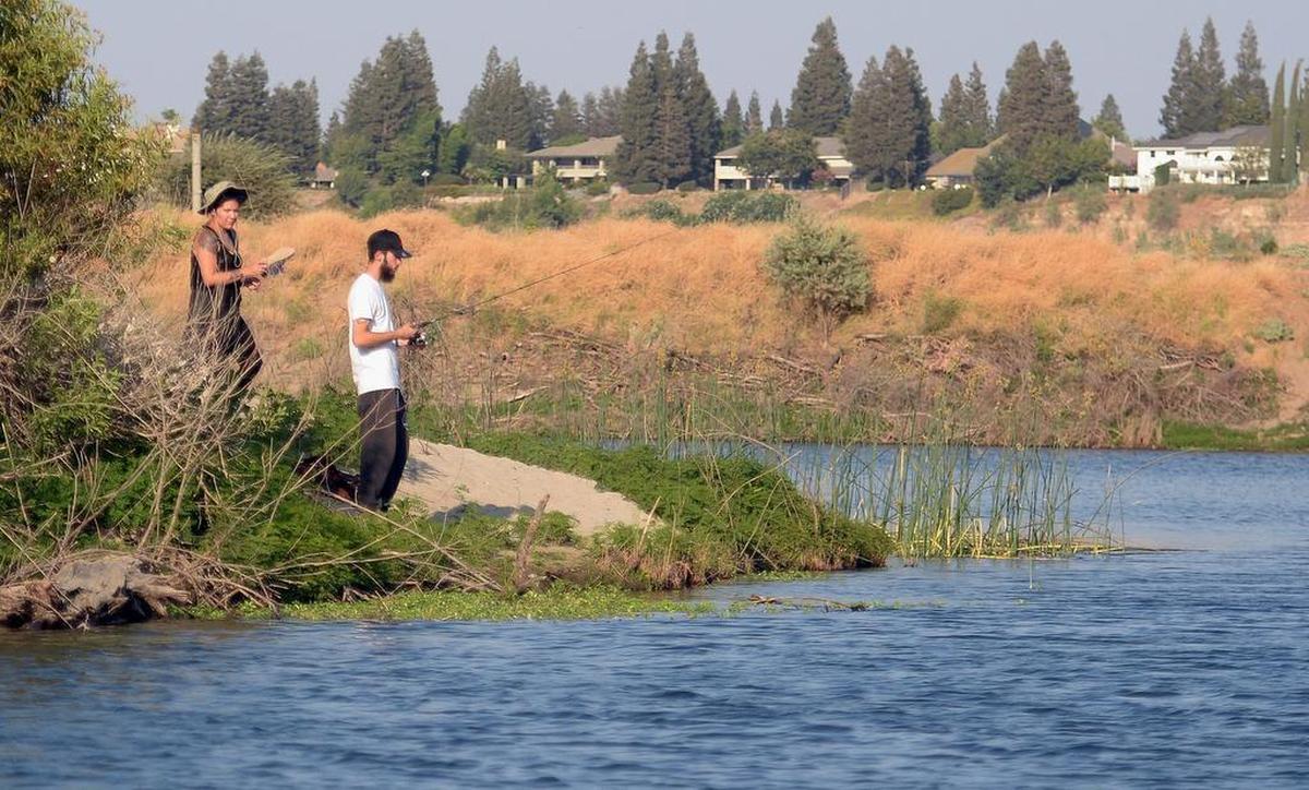 A couple fishes in a pond facing the San Joaquin River just north of Fresno on an August afternoon in 2017.