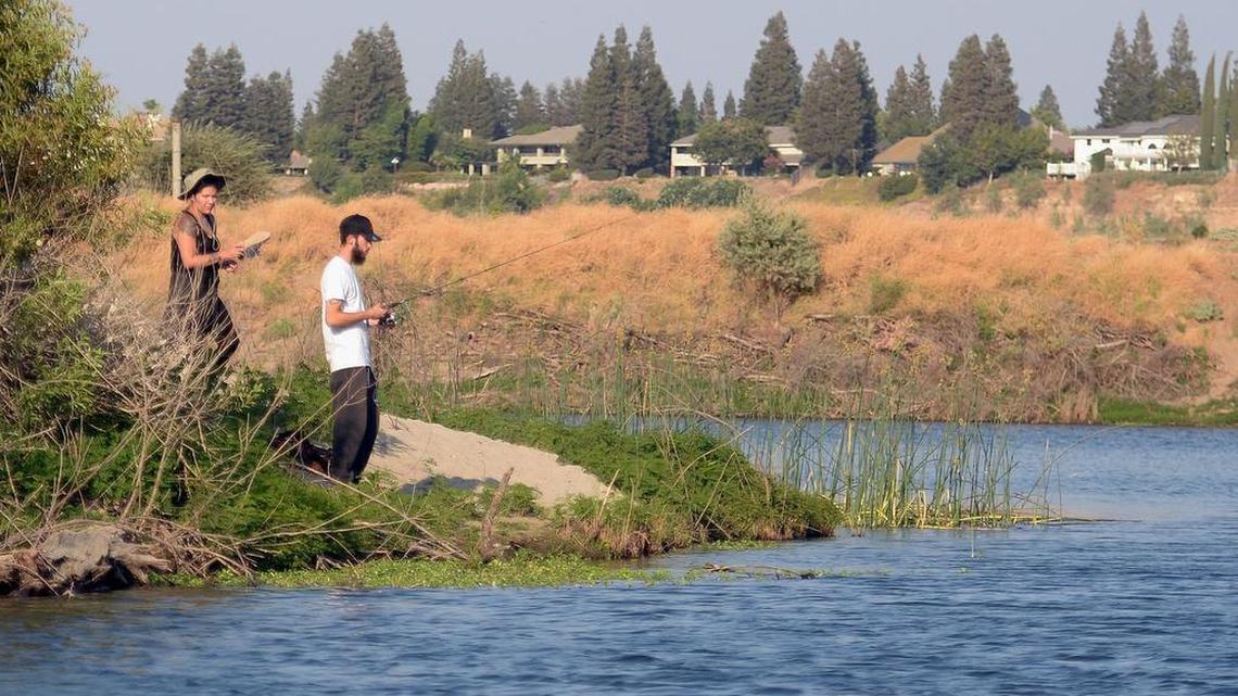 A couple fishes in a pond facing the San Joaquin River just north of Fresno on an August afternoon in 2017.