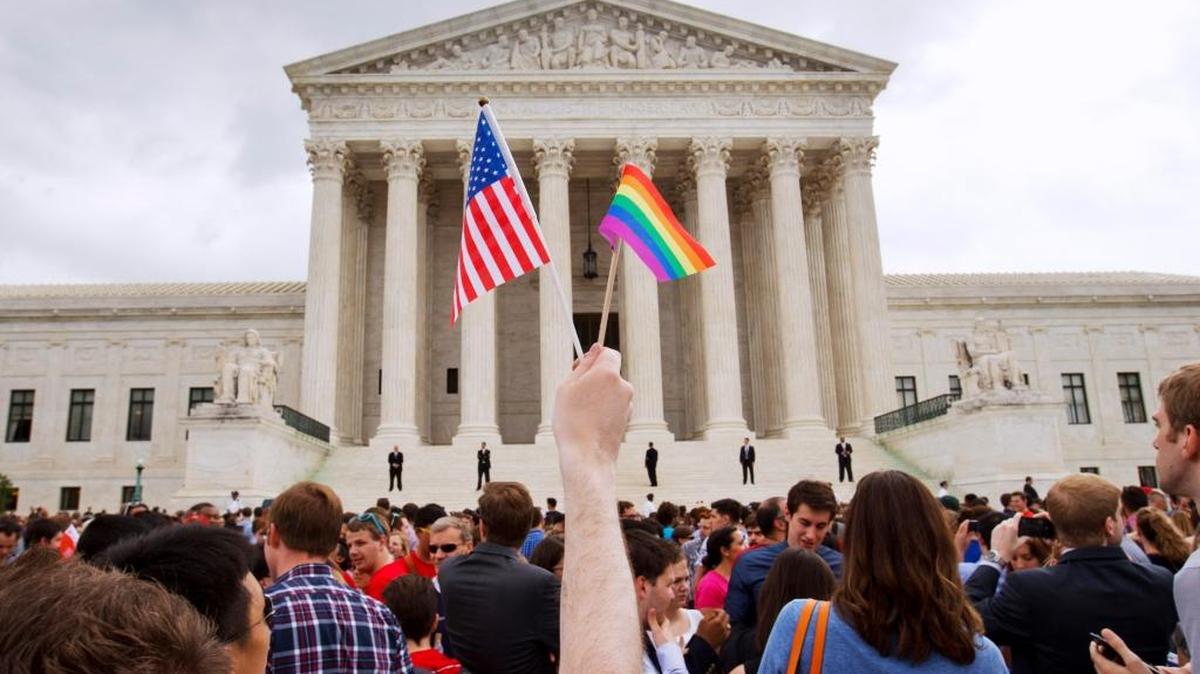 FILE - In this Friday June 26, 2015, photo, a man holds a U.S. and a rainbow flag outside the Supreme Court in Washington after the court legalized gay marriage nationwide by a 5-4 margin.