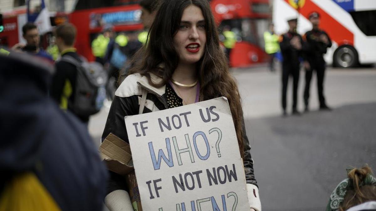 An Extinction Rebellion climate change protester holds a placard near the Bank of England, in the City of London, Thursday, April 25, 2019. Extinction Rebellion says it will end its remaining blockades in London on Thursday evening with a closing ceremony, after disrupting the British capital for 10 days. The non-violent protest group is seeking negotiations with the government on its demand to make slowing climate change a top priority. (AP Photo/Matt Dunham)
