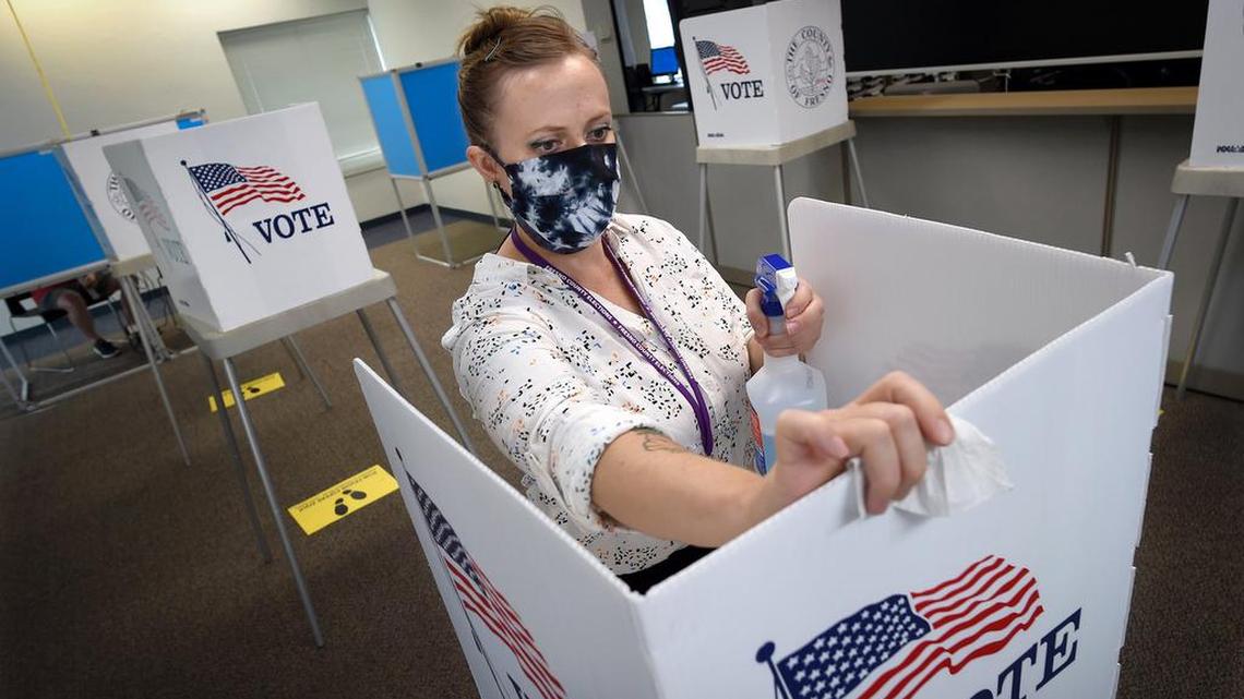 Fresno County Elections worker Kayla Lee sanitizes a voter’s booth after a person voted at the Fresno County Elections Office last fall.