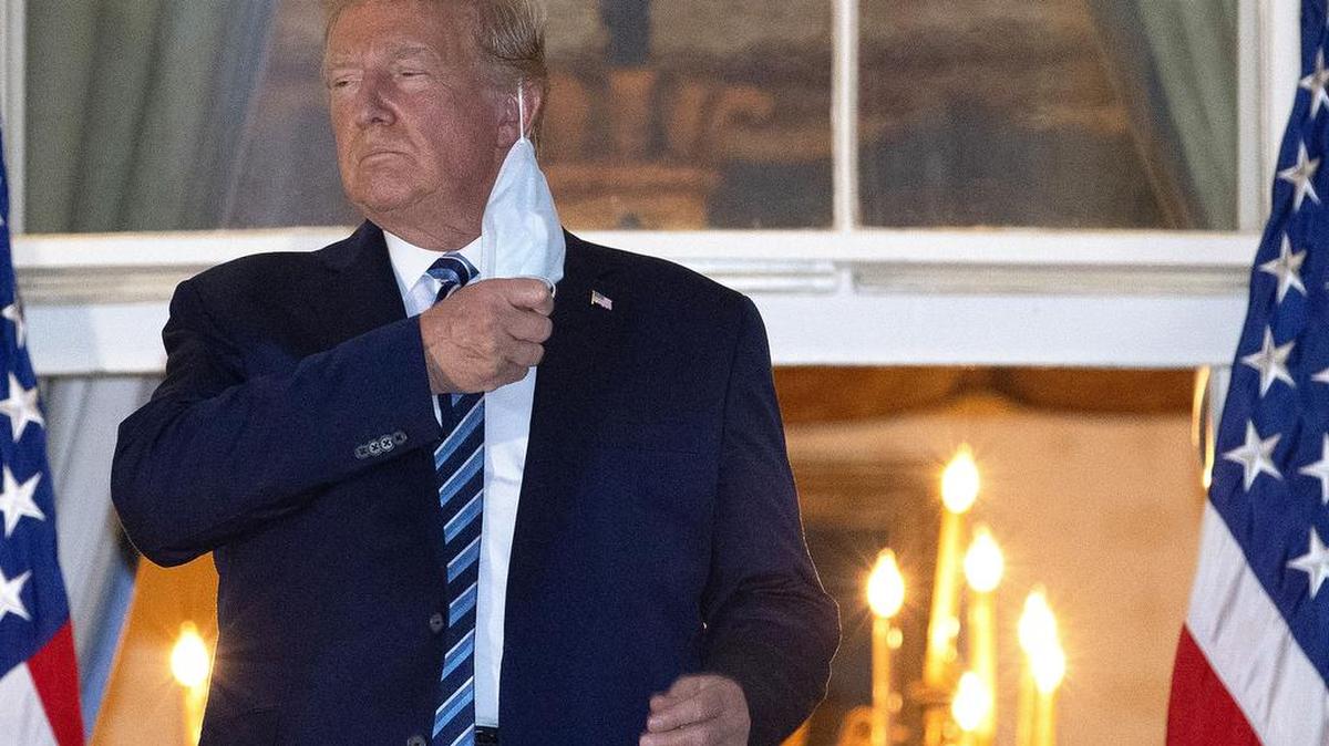President Donald Trump removes his mask at the White House.