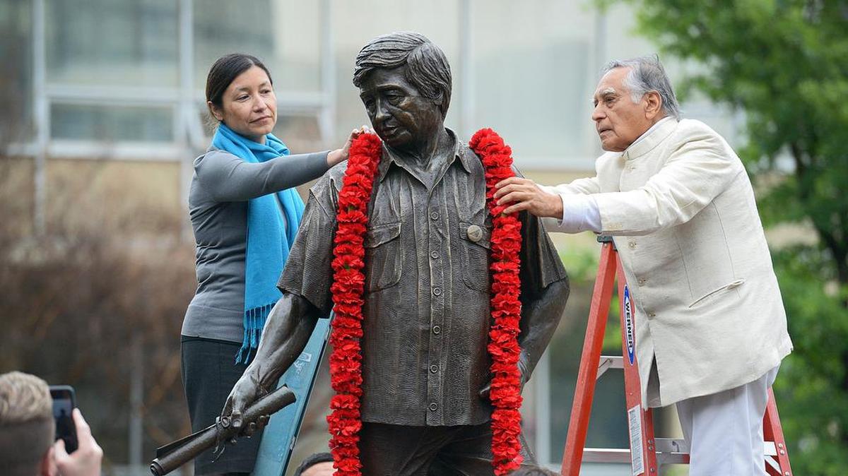 Julie Chávez Rodríguez, granddaughter of civil rights leader César E. Chávez, and Fresno State emeritus faculty member Dr. Sudarshan Kapoor, place a garland around the statue of Chávez in the Peace Garden at Fresno State in 2018.