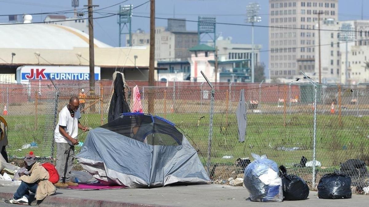 A homeless man sets up his tent following a clean-up sweep enforced by the police department near downtown Fresno as part of a city no-camping ordinance in this Fresno Bee file photo.