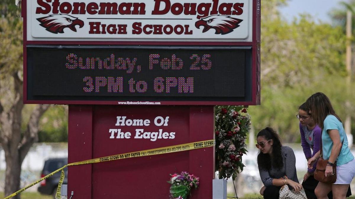 Mourners bring flowers as they pay tribute at a memorial for the victims of the shooting at Marjory Stoneman Douglas High School on Sunday, Feb. 25, 2018. The memorial was held during an open house as parents and students returned to the school for the first time since 17 people were killed in a mass shooting at the school in Parkland, Florida on Feb. 14, 2018.