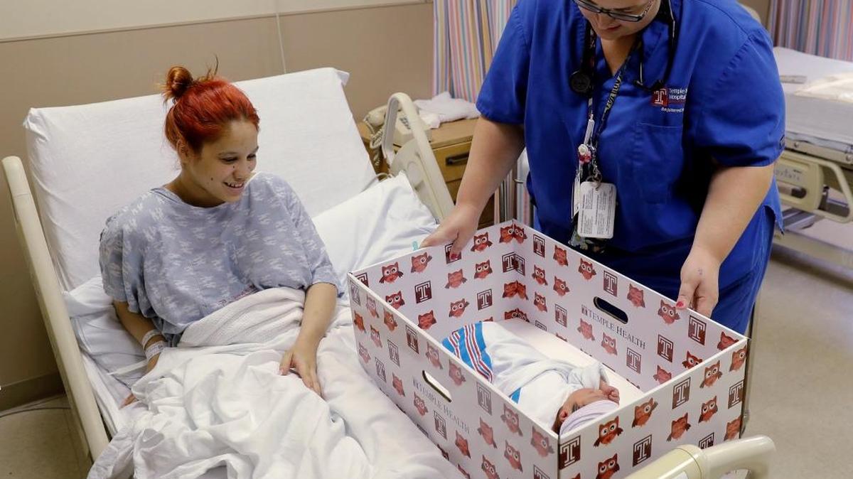 Keyshla Rivera smiles at her newborn son Jesus as registered nurse Christine Weick demonstrates a baby box before her discharge from Temple University Hospital in Philadelphia on May 6. In an effort to reduce infant mortality, the boxes, which are functioning bassinets complete with a sheet and mattress as well as essential baby supplies. will be given free-of-charge to all mothers who deliver at the hospital.