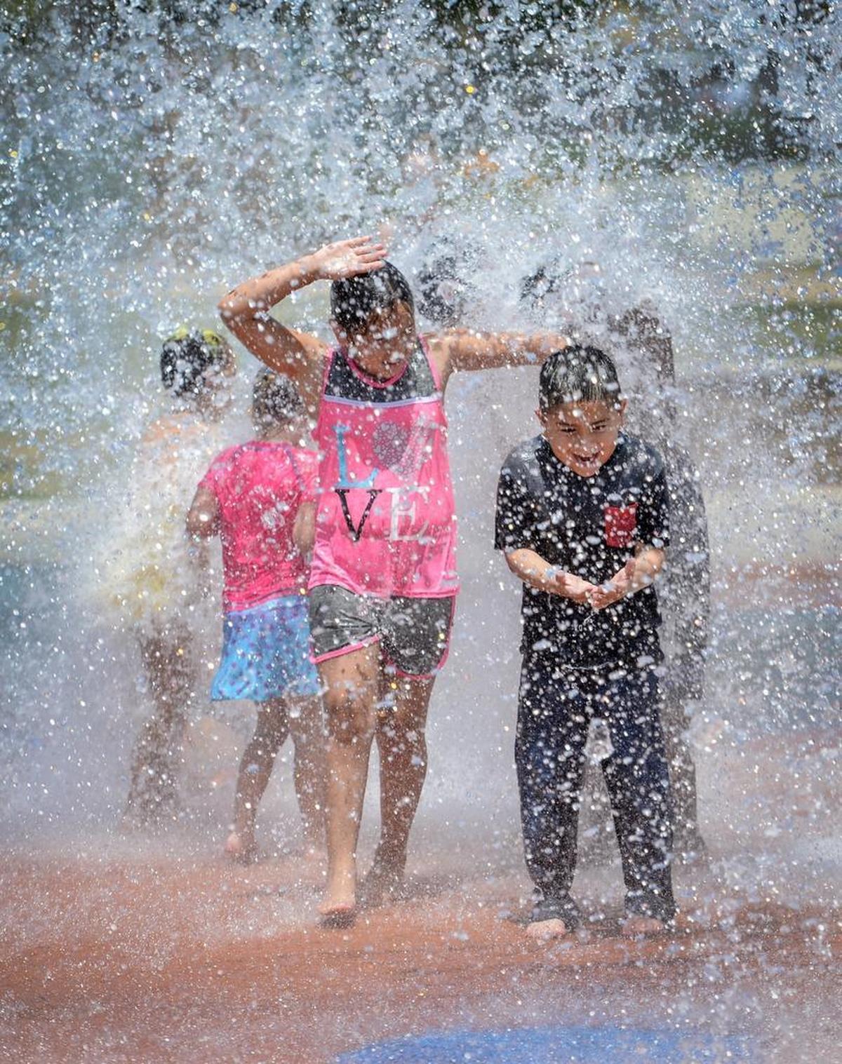 Kids are soaked as a giant bucket of water dumps over the top of them in the splash park at Inspiration Park in northwest Fresno as temperatures climb toward the triple digits on Saturday, June 23, 2018.