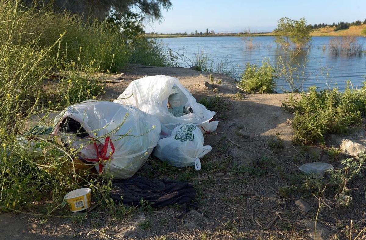 Bags of trash left on the bank of a pond in the River West-San Joaquin Parkway area north of Fresno on Friday, June 30, 2017.