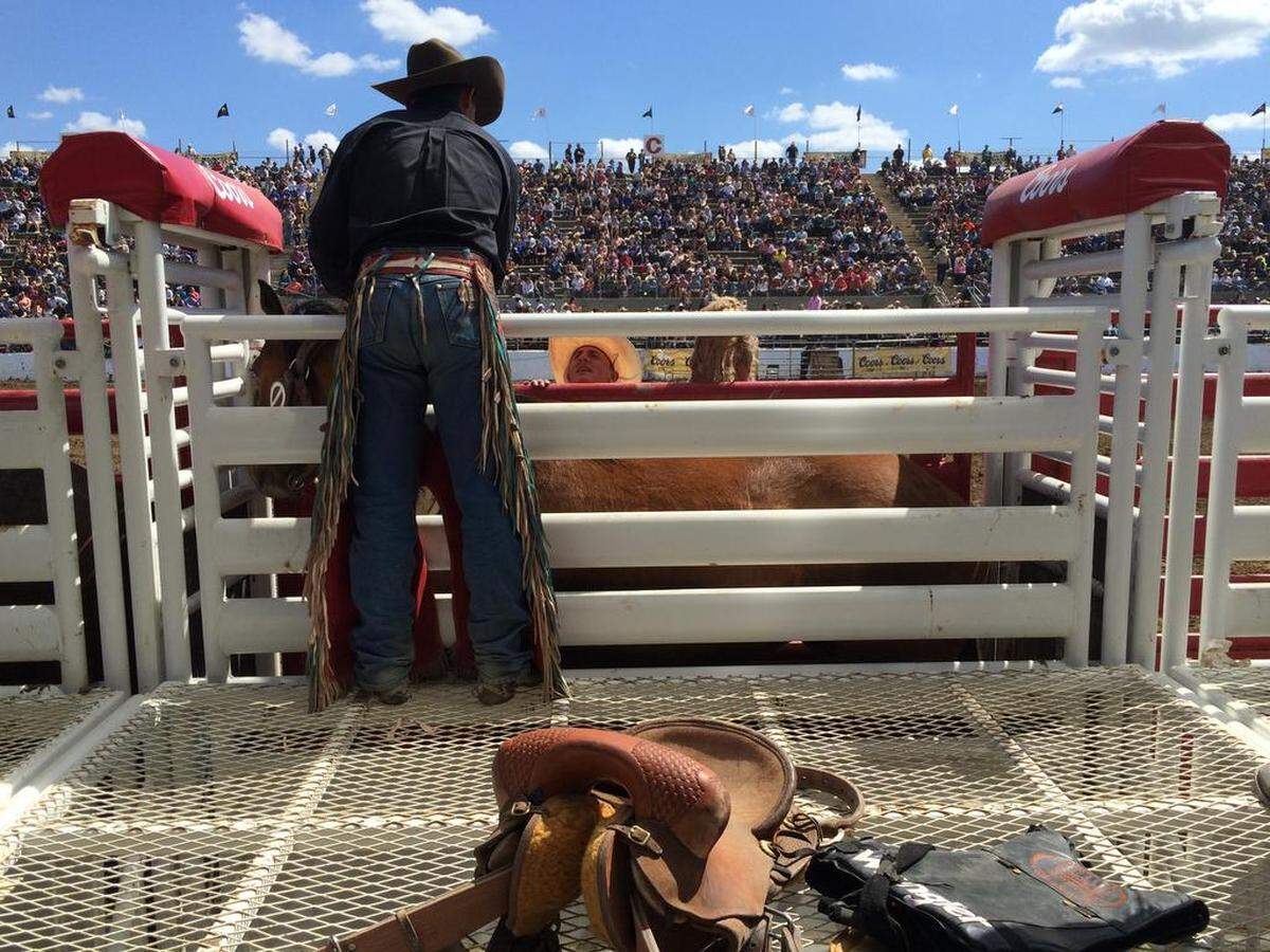 Saddle bronc rider Cody Wright leans over the rail to speak with son Rusty Wright during an appearance at the Clovis Rodeo. A new book titled "The Last Cowboys" by Pulitzer Prize winner and former Bee columnist John Branch chronicles how the Wright family uses its rodeo earnings to raise cattle and continue their way of life.
