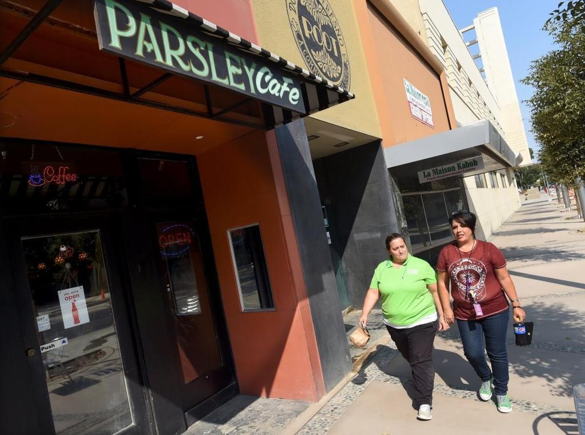 Fulton Mall workers Lesley Verret, left, and Monica Alvarado pass by the front entrance of the Parsley Garden Cafe in downtown Fresno. For more than a year, construction has made it difficult for customers to access any of the businesses along what used to be the Fulton Mall.