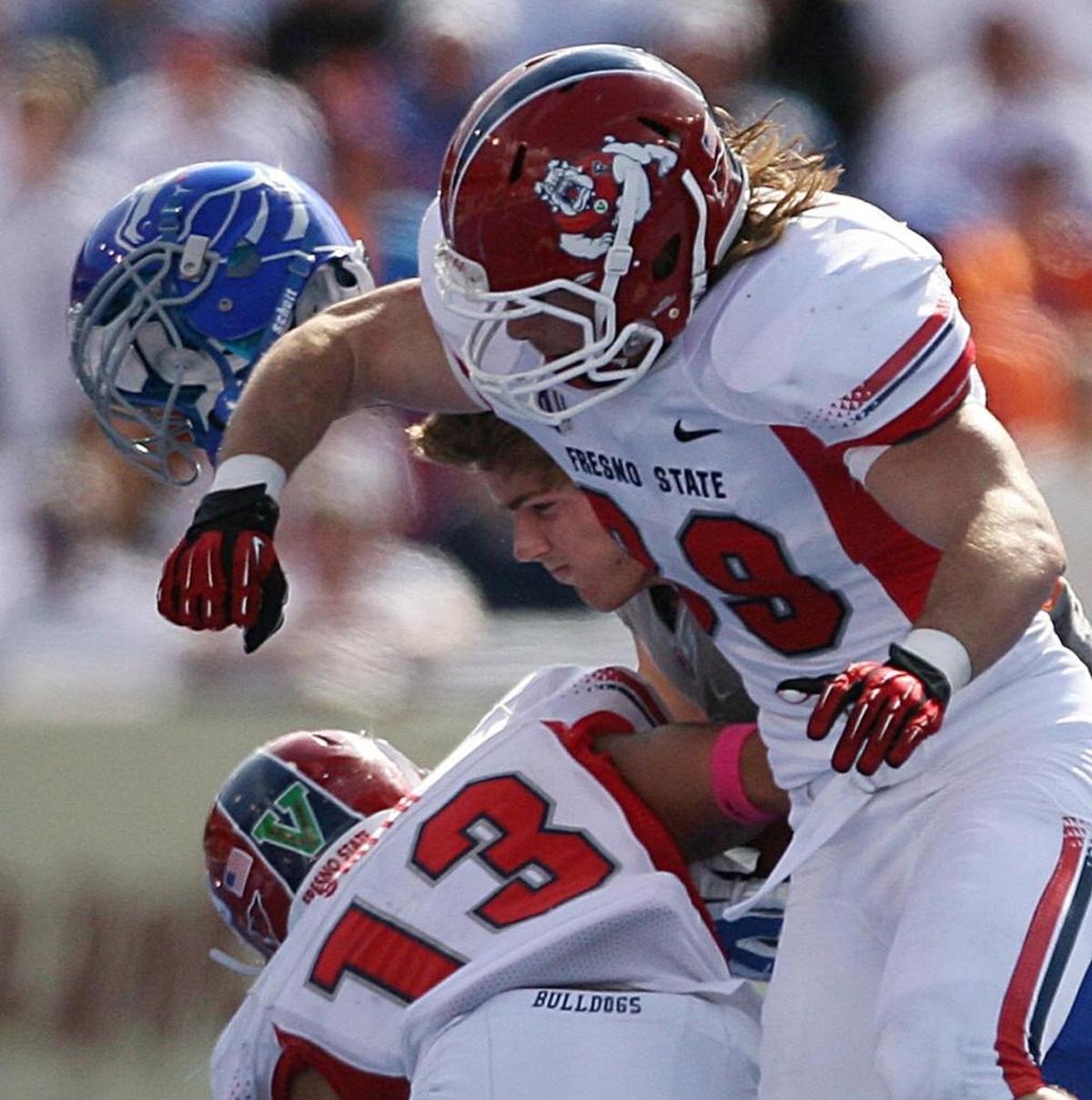 Boise State receiver Kirby Moore catches the ball but loses his helmet on a hit by Fresno State defenders Shawn Plummer (39) and Derron Smith (13) during a 2012 game in Boise, Idaho.