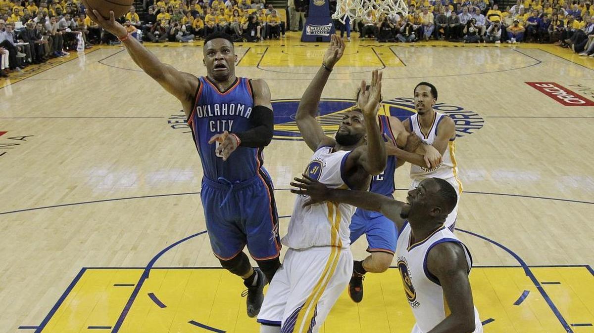 Oklahoma City guard Russell Westbrook, left, drives to the hoop against Warriors center Festus Ezeli (31) and forward Draymond Green, right, for two of his 19 third-quarter points during the Thunder’s 108-102 victory Monday night in Oakland.