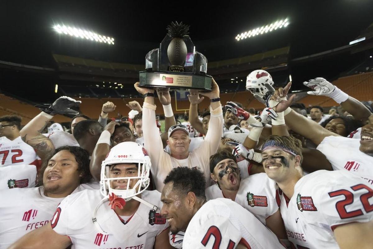 Fresno State coach Jeff Tedford, center, holds up the Hawaii Bowl championship trophy after the Bulldogs defeated Houston 33-27 on Dec. 24, 2017, in Honolulu, the program’s first bowl win in a decade.