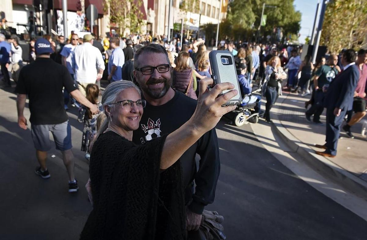 Nina and Jeff Kenny pose for a selfie as pedestrians walk the newly opened Fulton Street on Saturday in downtown Fresno.