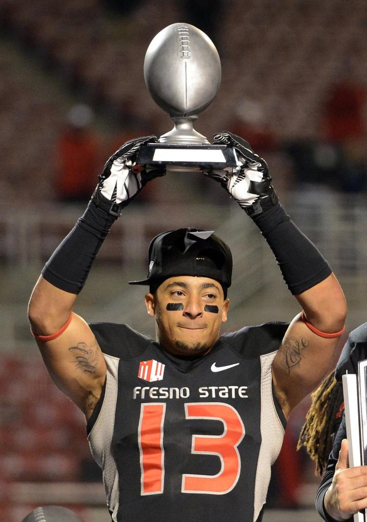 Fresno State’s Derron Smith holds up the defensive player of the game trophy after the Bulldogs beat Utah State in 2013 to win the inaugural Mountain West Conference championship. Fresno State returns to the title game Saturday when it plays at Boise State.