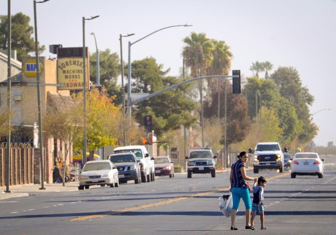 A mother and son cross Oller Street in the somewhat quiet western Fresno County city of Mendota.
