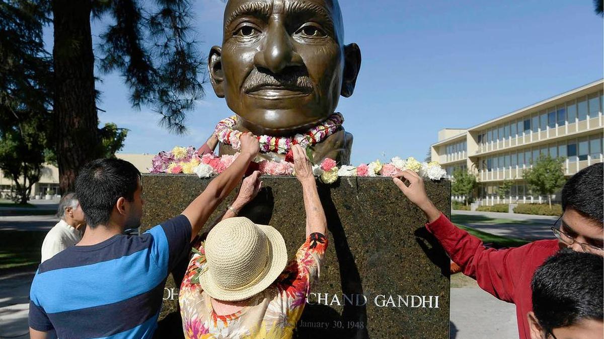 Carnations are placed on the bronze bust of Mahatma Gandhi at Fresno State’s Peace Garden during a ceremony honoring Gandhi’s 145th birthday.