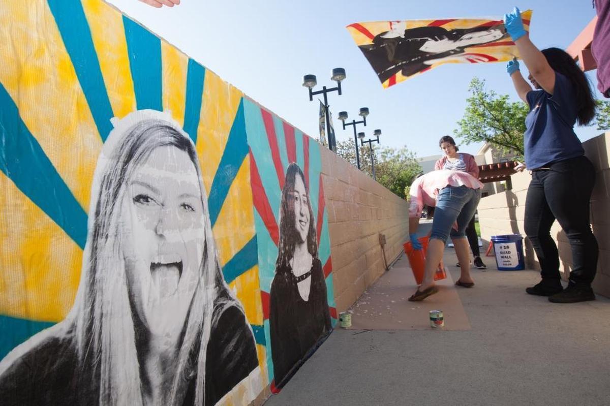 Daisy Robles holds a print in the wind. /The first image on wall is of Katie McQuone, a video production instructor.