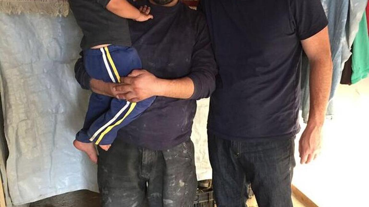 The Rev. Will Stoll, right, pastor of Fresno’s Northwest Church, visits with a Syrian father and son. They live in a refugee camp tent in Marg, Lebanon, about a mile from the Syrian border.