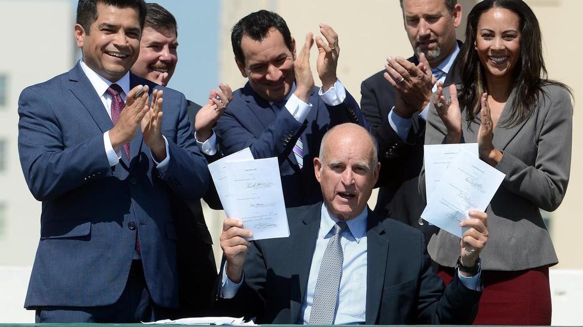 Gov. Jerry Brown holds up four bills he signed related to climate change on Wednesday, Sept. 14, 2016, in downtown Fresno. One of the bills, AB1613, directed $900 million in cap-and-trade funds to greenhouse gas reducing programs that benefit disadvantaged communities, support clean transportation and protect natural ecosystems.