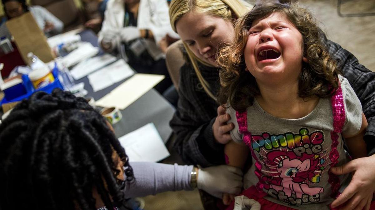 Flint resident Sarah Truesdail holds her daughter Gabriella Venegas, 5, as she screams out with tears rolling down her face while a health official pricks her finger with a needle for a free lead test on Feb. 8 at Carriage Town Ministries in Flint. Molina Healthcare provided children up to 6 years of age with free lead testing, as well as water filters for families to take home and install.