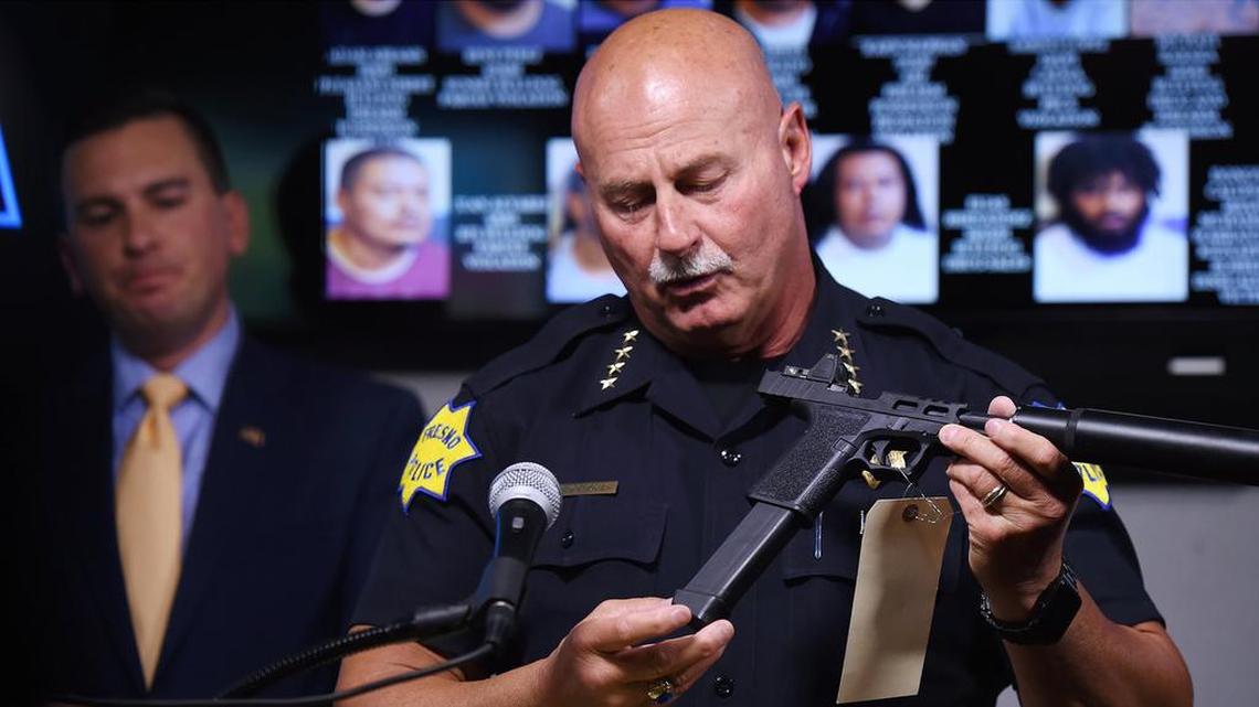 Fresno Chief of Police Jerry Dyer holds one of many weapons seized in an anti-gang operation, with HSI Special Agent in Charge Jeff Brannigan to the far left during a press conference Tuesday, May 28, 2019 in Fresno.