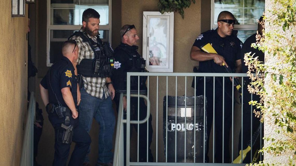 Fresno police officers stand outside an apartment where a man wanted on domestic violence charges was holed up with a knife in southwest Fresno on Friday, Sept. 7, 2018.