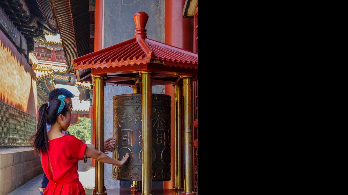 
A young couple share a moment at a prayer wheel at the Lama Temple, Beijing. 
