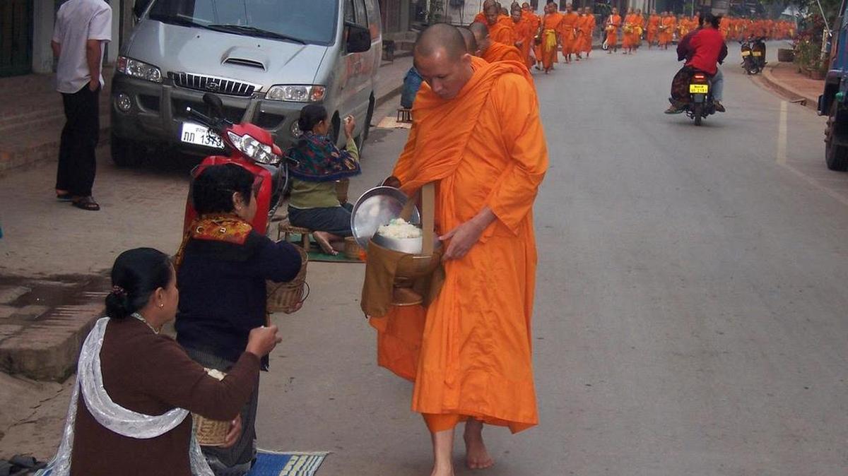 Laotian townspeople give rice balls to monks as they come by. In a Valley Voice, Phil Fullerton writes how the procession transformed his view of Thanksgiving.
