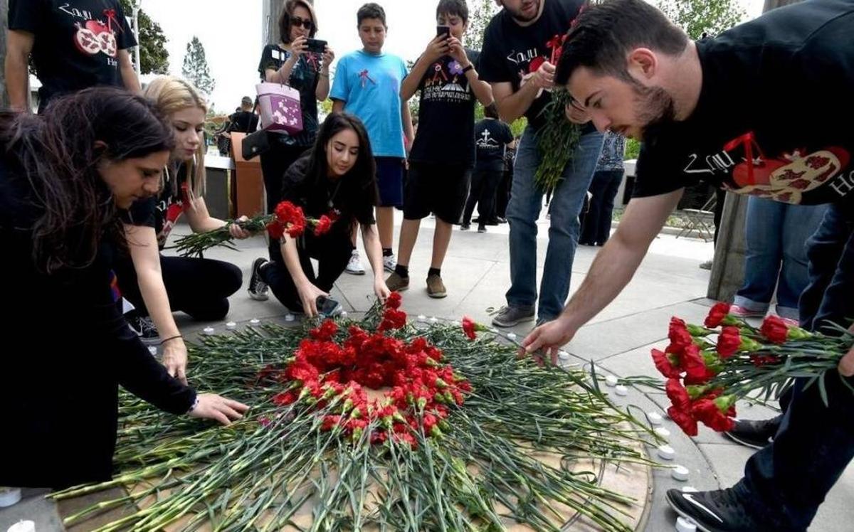 People dressed in black in solidarity of remembrance of the Armenian Genocide, lay red carnations in a circle at the conclusion of Fresno State’s 2016 Armenian Genocide Commemoration at the Armenian Genocide Monument.