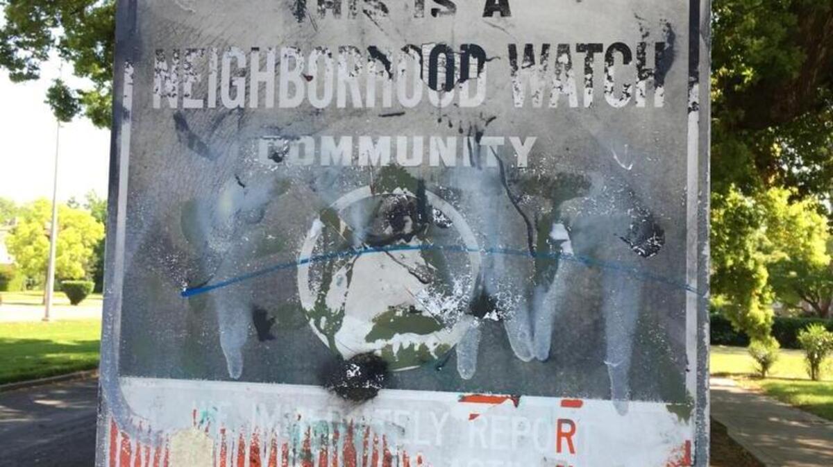 A Neighborhood Watch sign is defaced with graffiti on Huntington Boulevard.