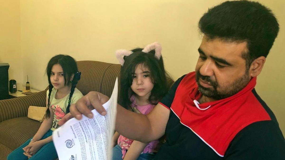 Syrian refugee Mahmoud Mansour, sitting with his daughters Sahar, 5, and Ruba, 11, holds documents for his U.S. resettlement application at his rented apartment in Amman, Jordan, Wednesday, June 27, 2018. Mansour, who had been tapped for possible resettlement to the United States, says his hopes have been crushed for good by the Supreme Court's decision to uphold a Trump administration travel ban for Syria and four other Muslim-majority countries.