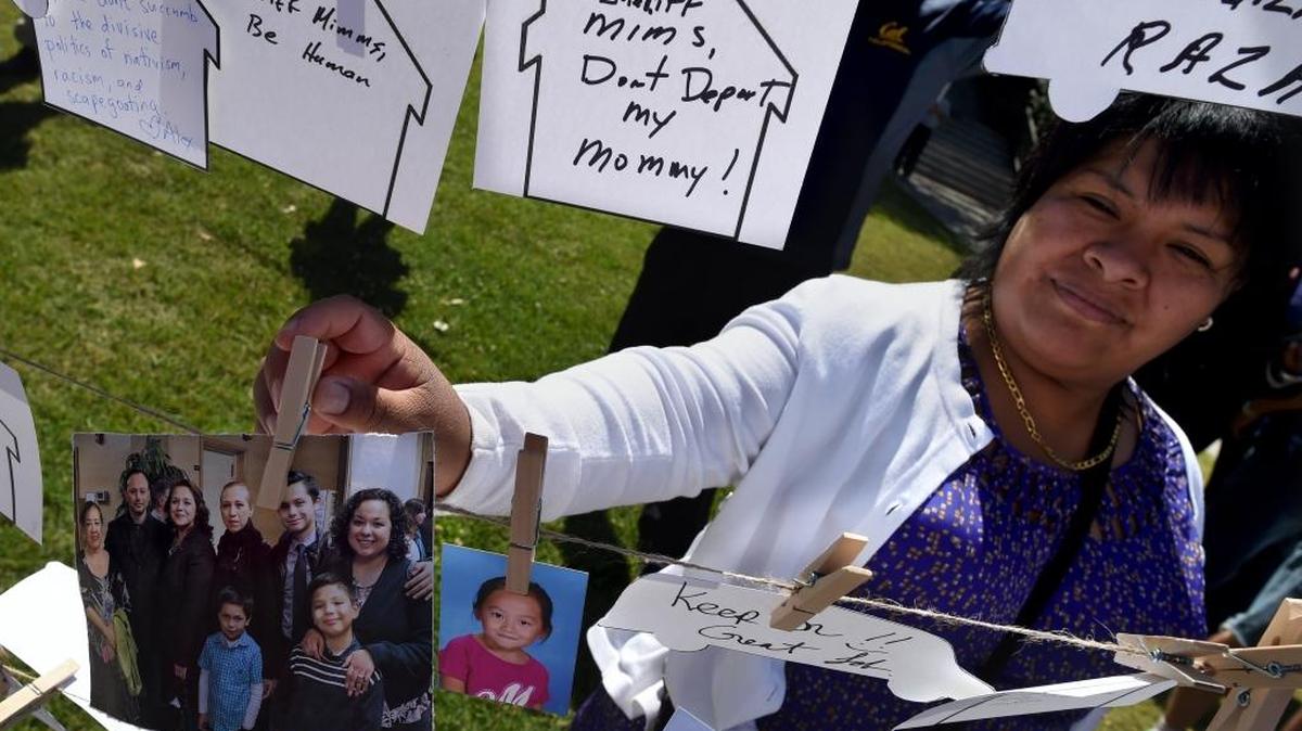 Eugina Melesic of Fresno pins a photo to others hanging in a display with messages from families urging Sheriff Margaret Mims not to collaborate with deportation officials April 12, 2017.
