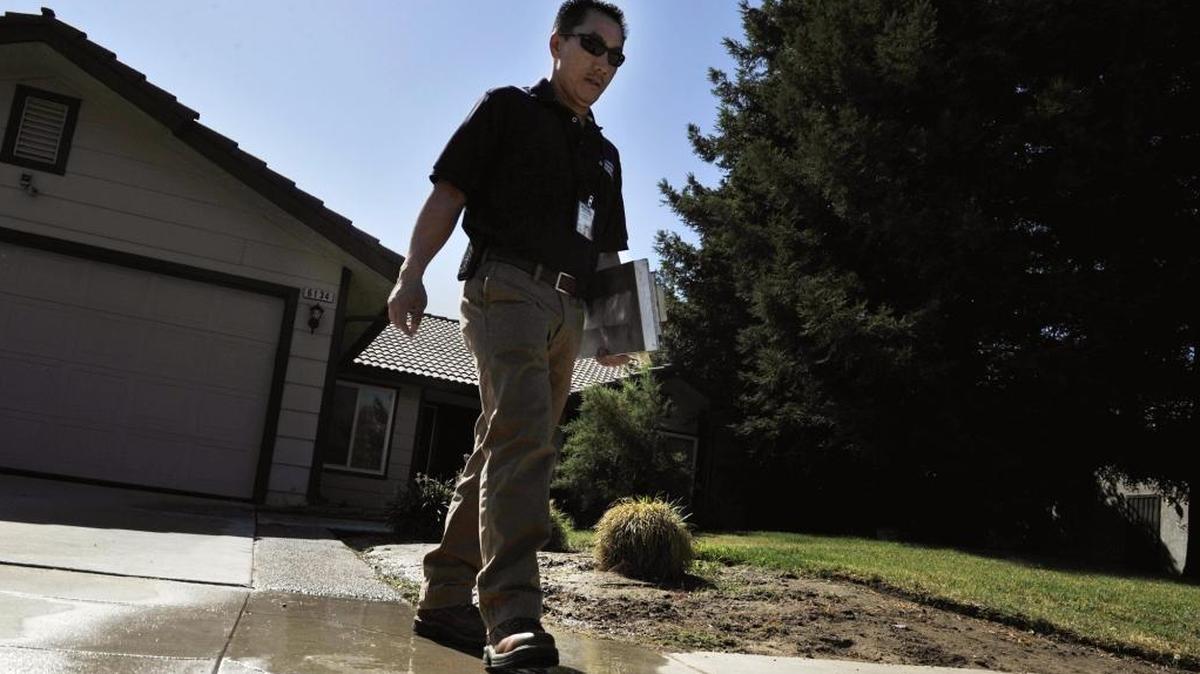 Tou Moua, a water conservation representative for the city of Fresno, leaves a home where he left a notice for use of sprinklers during a prohibited time of day, flooding gutters and causing flooding to a neighbor’s property.