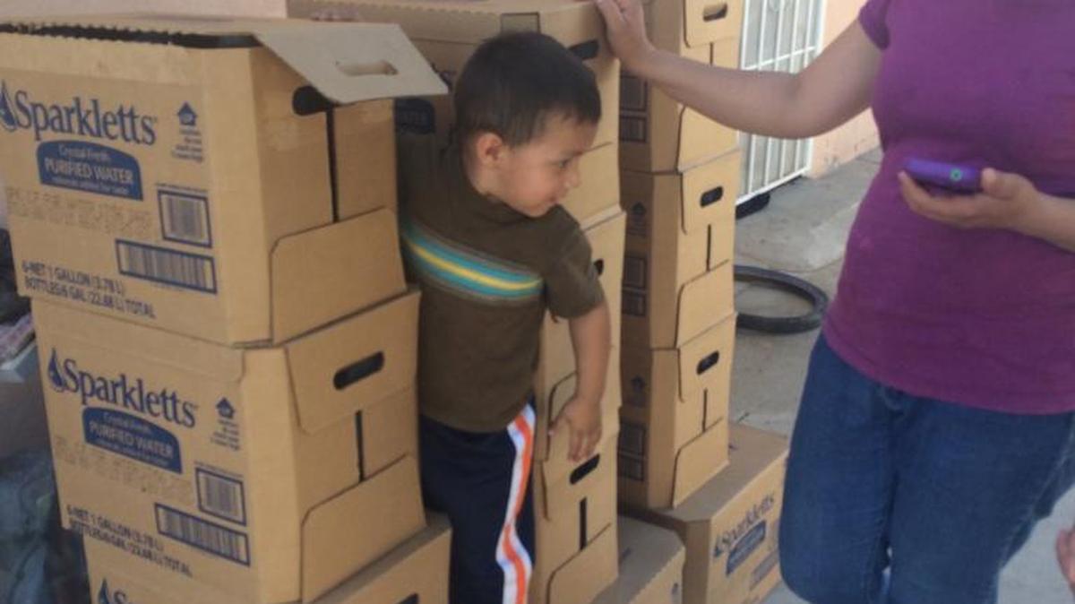 A mom and her two children unpack their monthly delivery of bottled water in El Porvenir. The woman, whose first name is Maritza asked that her last name not be used.