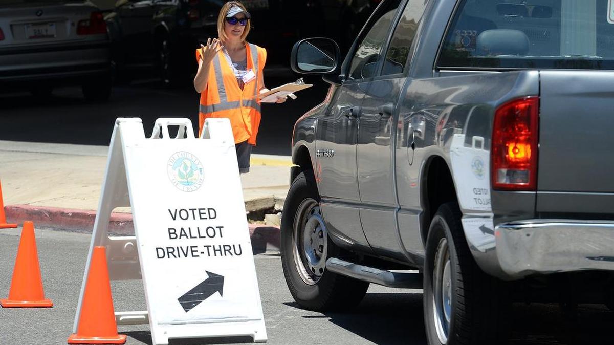 Poll worker Holly Brown guides a truck through the drive-through lane set up outside the Fresno County Registrar of Voters office during the June primary. Voters were given the opportunity to drop off their voted ballots without getting out of their vehicles.