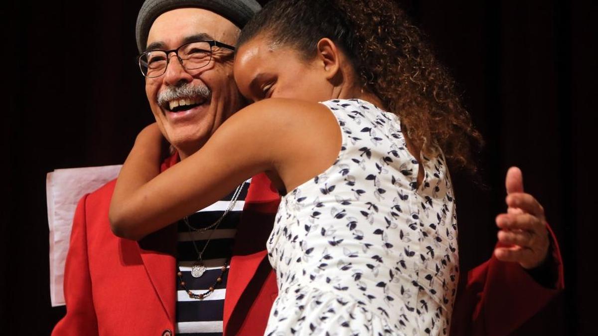 U.S. Poet Laureate Juan Felipe Herrera gets a hug from a girl who helped read one of his poems at the conclusion of the inaugural LitHop.