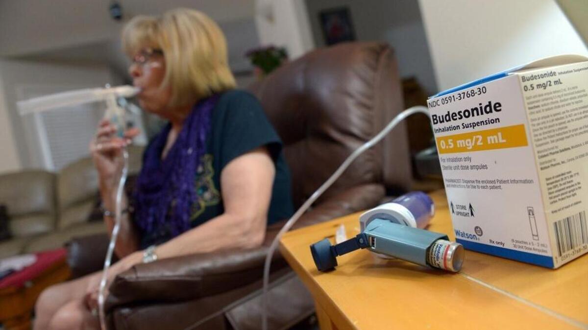 Fawn Olvera of Clovis uses a nebulizer machine to inhale her medicine to help her breathe in her living room on April 6. Olvera has asthma and air pollution makes it worse.