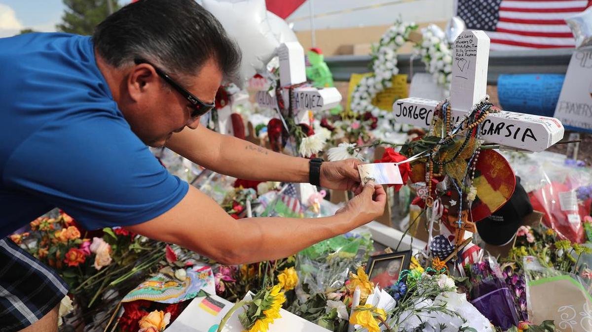 Ray Pacheco places a pin on the marker for Jorge Calvillo García, his daughter-in-law’s uncle whom he knew very well, at the makeshift memorial for the victims of the mass shooting at a Walmart store in El Paso, Texas, on Wednesday, Aug. 7, 2019.