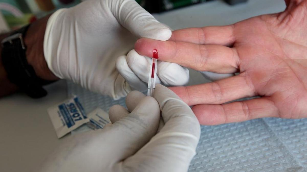 HIV counselor and tester Darren Edwards, from AIDS Health Care Foundation, pricks the finger of Sean Crockett to test for HIV and STD in 2013 at the University of Southern California.