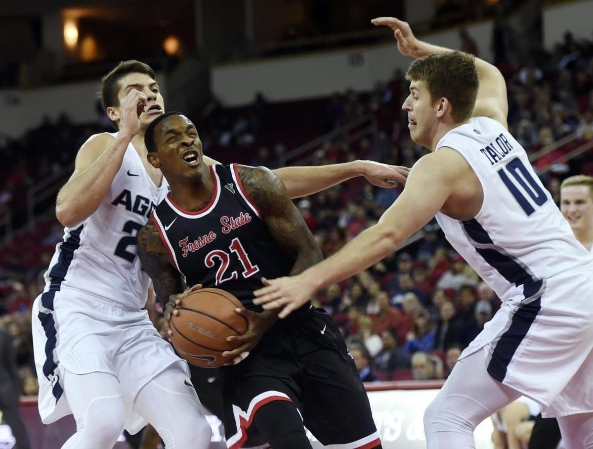 Fresno State guard Deshon Taylor, center, is fouled with Utah State's Diogo Brito, left, and Quinn Taylor, right, in a 65-62 loss to the Aggies Saturday, Jan. 27, 2018 in Fresno. Taylor led the Bulldogs with 15 points.