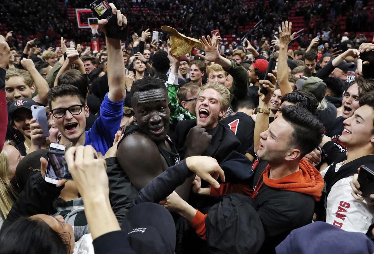 San Diego State forward Aguek Arop, center left, is swarmed by fans after San Diego State defeated Nevada 65-57 last month at Viejas Arena.