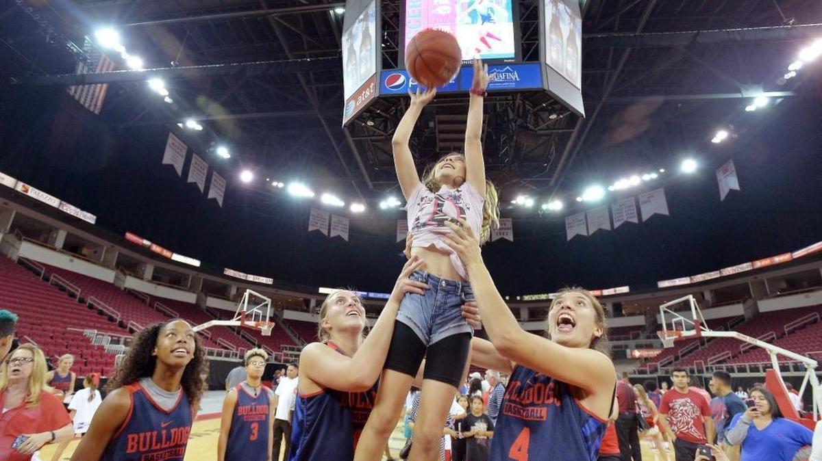 Ashley Rossen, 10, of Madera Ranchos gets a little help from Fresno State’s Raven Johnson (2), Brittany Aikens (3), Anais Kirvan (13) and Bego Faz Davalos (4) as she shoots hoops with the team at Fresno State’s Basketball Community Night on Oct. 22, 2015, at Save Mart Center. Fans were introduced to the Bulldogs’ men’s and women’s players and given the opportunity to get autographs, receive free posters and shoot hoops with the teams.