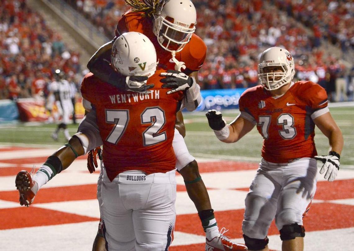 Fresno State teammates congratulate offensive lineman Austin Wentworth after he scored a touchdown on a trick play against Cal Poly in a Sept. 7, 2013, game. Undrafted out of college, he made the roster of the Minnesota Vikings but will call it a career after just one season because of complications from blood clots in his legs.