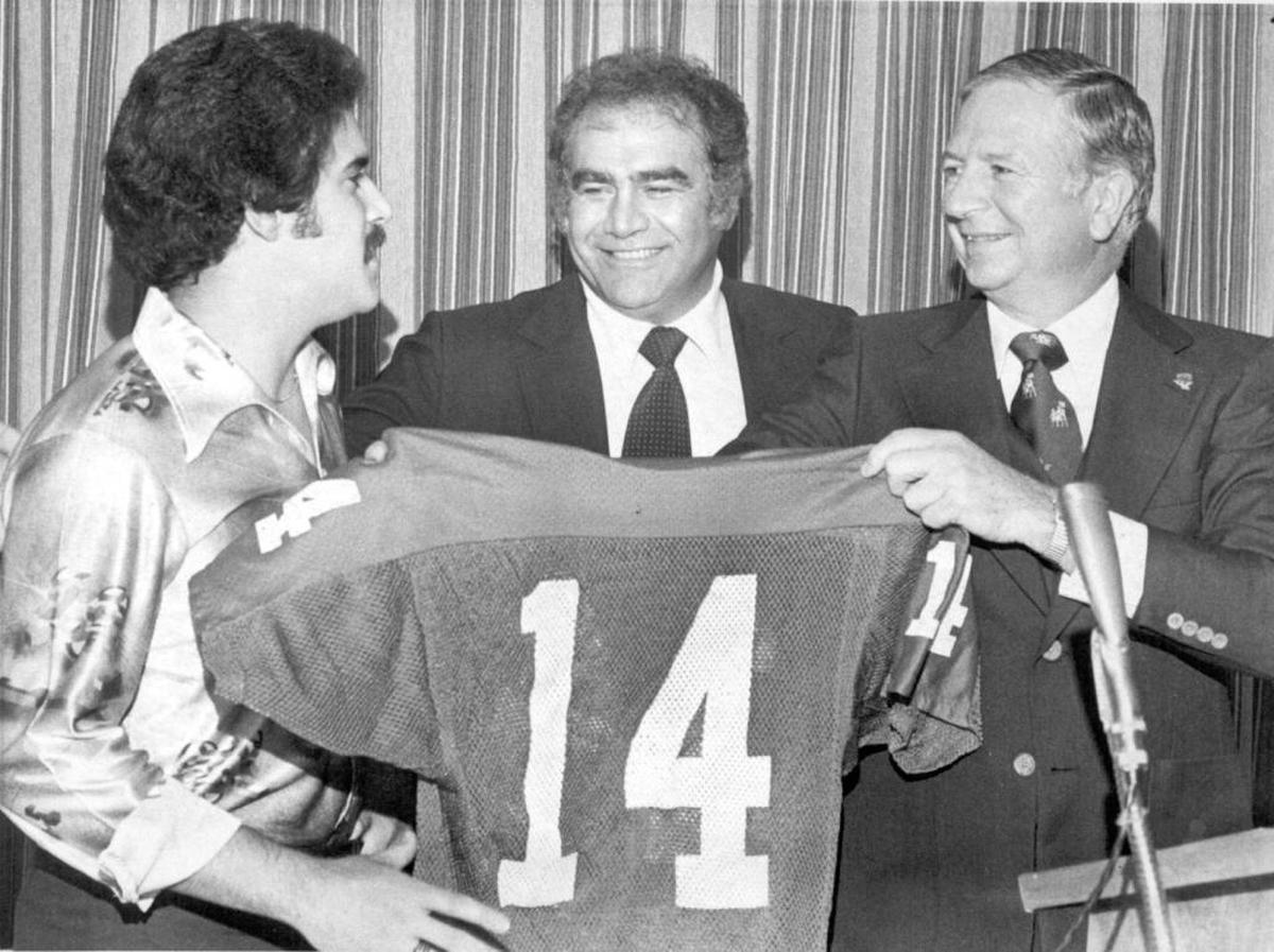 Former Fresno State kicker Vince Petrucci, left, holds up his retired No. 14 jersey with coach Bob Padilla, center, and athletic director Gene Bourdet.