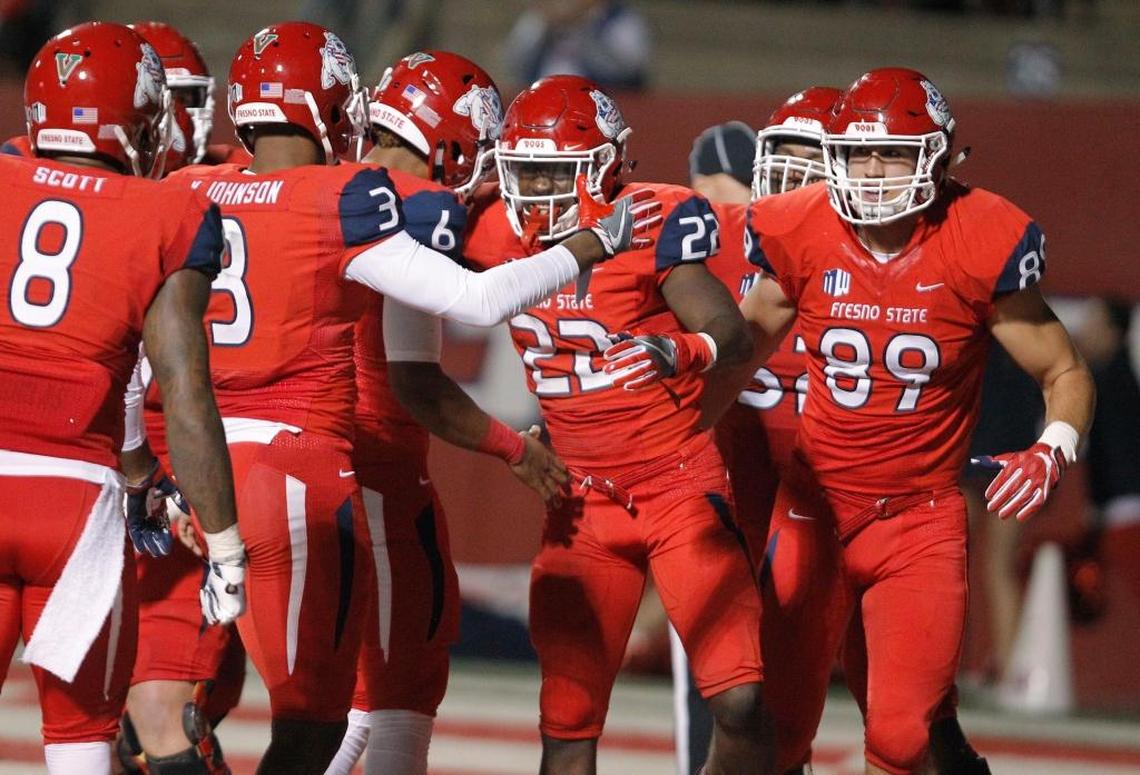 Fresno State running back Jordan Mims (22) celebrates with KeeSean Johnson (3), Da’Mari Scott (8), Kyle Riddering (89) and Marcus McMaryion (6) after scoring a touchdown in the fourth quarter of the Bulldogs’ 20-13 victory over BYU at Bulldog Stadium, Saturday, Nov. 4, 2017. The win made Fresno State bowl eligible one season after going just 1-11.