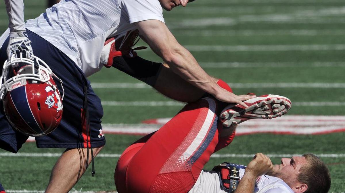 
 Head strength coach Joey Boese, left, helps inside linebacker Jeff Camilli stretch during Fresno State's annual Spring Showcase in March. Camilli, through work in the spring and summer, has cut his weight down by about 15 pounds and was noticeably quicker at the opening practice of fall camp.
