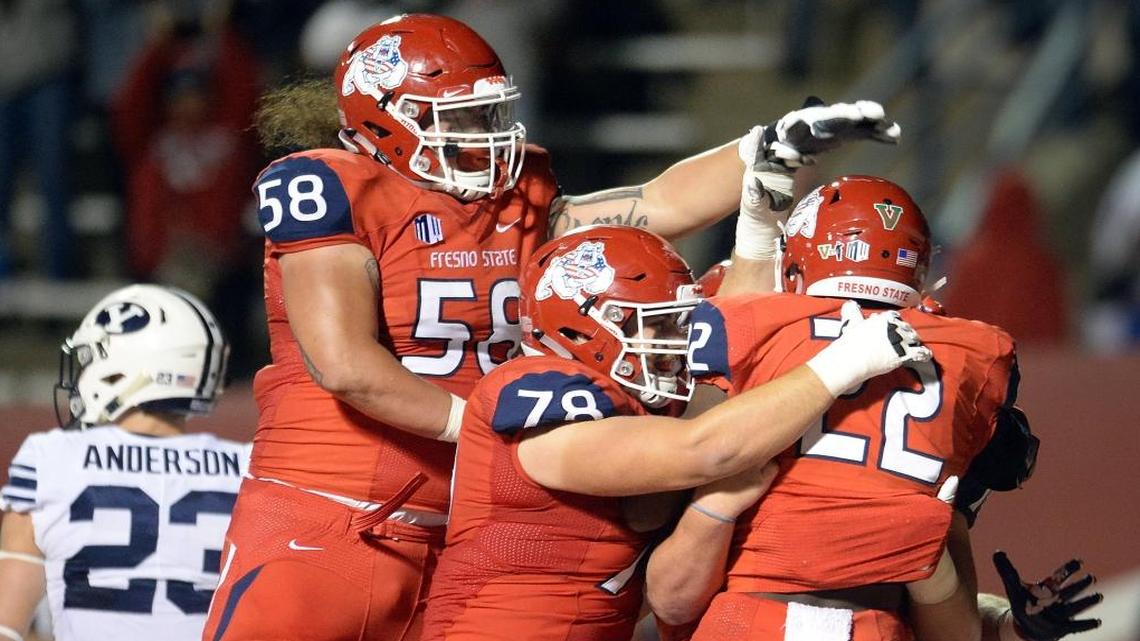 Fresno State’s Jordan Mims, right, is mobbed by teammates including offensive linemen Christian Cronk (58) and David Patterson (78) after scoring the winning touchdown against BYU at Bulldog Stadium on Saturday, Nov. 4, 2017. Mims had 20 carries for 54 yards and two touchdowns. He had six straight carries to start the fourth quarter to cover the final 15 yards of the drive.